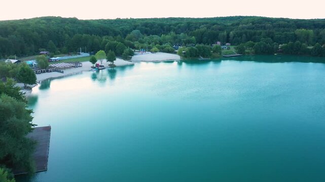 The lake is located in an abandoned quarry with blue water. Scenic aerial view of an abandoned quarry with clear blue water transformed into a public beach and recreational park with swimmers.