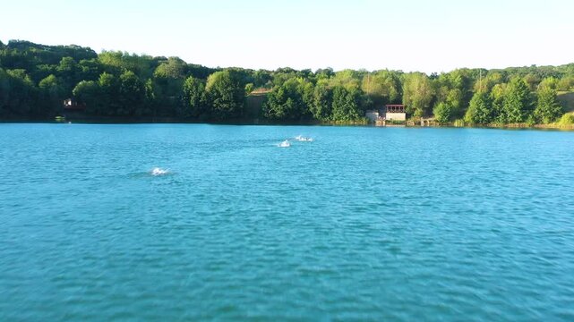 The lake is located in an abandoned quarry with blue water. Scenic aerial view of an abandoned quarry with clear blue water transformed into a public beach and recreational park with swimmers.