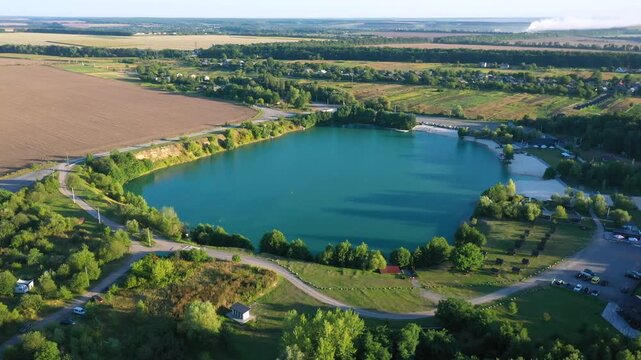 The lake is located in an abandoned quarry with blue water. Scenic aerial view of an abandoned quarry with clear blue water transformed into a public beach and recreational park with swimmers.