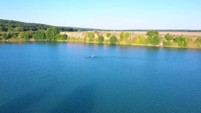 The lake is located in an abandoned quarry with blue water. Scenic aerial view of an abandoned quarry with clear blue water transformed into a public beach and recreational park with swimmers.