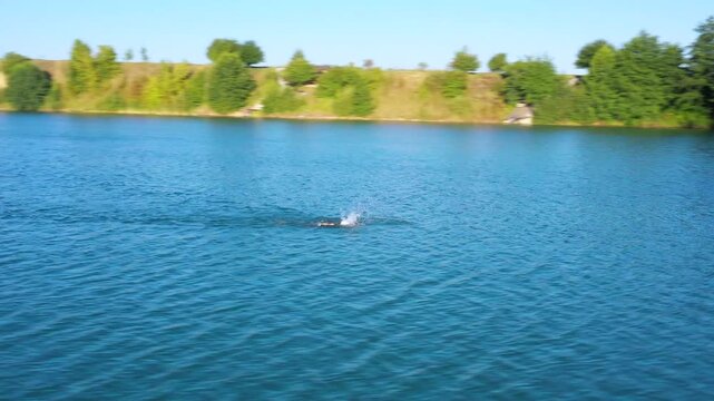 The lake is located in an abandoned quarry with blue water. Scenic aerial view of an abandoned quarry with clear blue water transformed into a public beach and recreational park with swimmers.