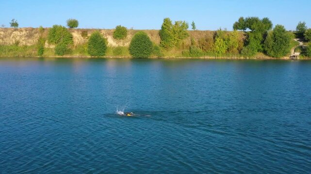 The lake is located in an abandoned quarry with blue water. Scenic aerial view of an abandoned quarry with clear blue water transformed into a public beach and recreational park with swimmers.