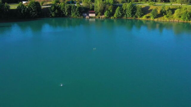 The lake is located in an abandoned quarry with blue water. Scenic aerial view of an abandoned quarry with clear blue water transformed into a public beach and recreational park with swimmers.