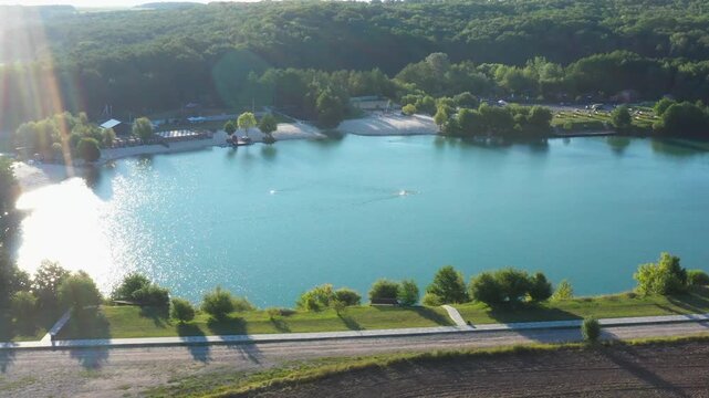 The lake is located in an abandoned quarry with blue water. Scenic aerial view of an abandoned quarry with clear blue water transformed into a public beach and recreational park with swimmers.
