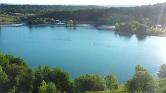 The lake is located in an abandoned quarry with blue water. Scenic aerial view of an abandoned quarry with clear blue water transformed into a public beach and recreational park with swimmers.