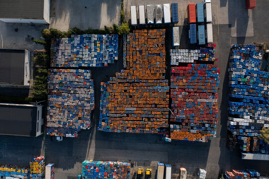 Aerial view of a large industrial storage facility filled with rows of colorful plastic barrels and shipping containers in Roeselare, Flanders, Belgium.