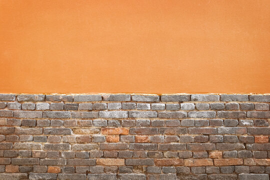 Horizontal contrast between smooth orange plaster wall and old rustic brick textured background.