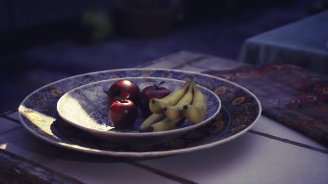Plate of fruit on table, ceramic bowl with apples, bananas and pomegranate, soft moody light casting deep shadows, Mutrah Souq stall ambiance with vintage