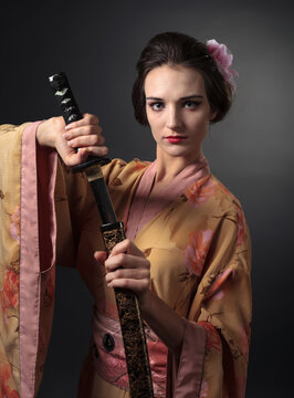 Elegant woman in a floral Japanese kimono holding a traditional katana.