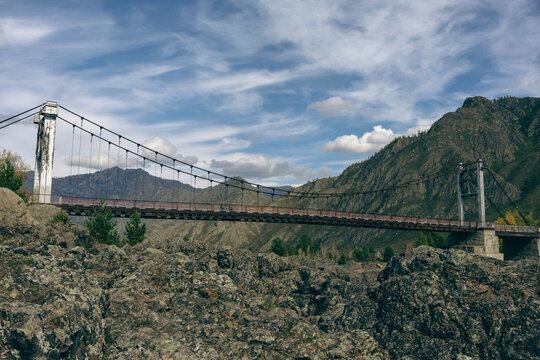 Suspension cable bridge spanning over rocky gorge in mountain landscape