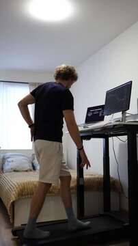 Vertical screen happy student celebrates passing his exams while walking on a treadmill feeling relieved and proud after completing a difficult academic session successfully at home