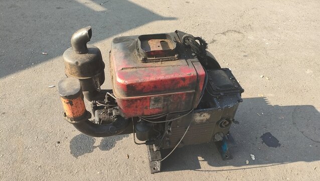 Old diesel engine machine and industrial power unit with exhaust pipe on concrete ground. Concept of heavy machinery repair, agricultural tool hardware, and antique motor