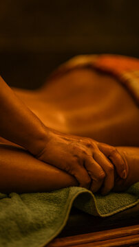 Professional massage therapist performing a relaxing body treatment in a dim spa environment