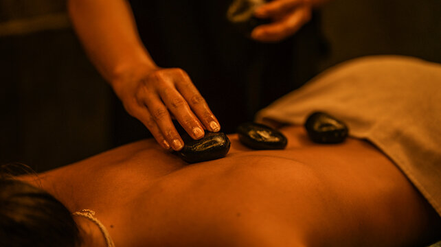 Professional hot stone massage therapy session in a tranquil and dimly lit wellness spa setting