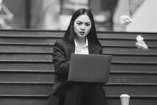Asian woman in sitting at stairway outdoor have a stressed, after being laid off unemployed. Desperate be out of work.
