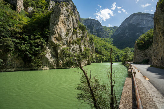  Scenic road along the Candigliano river enclosed between the towering limestone cliffs of Furlo Gorge, Italy.