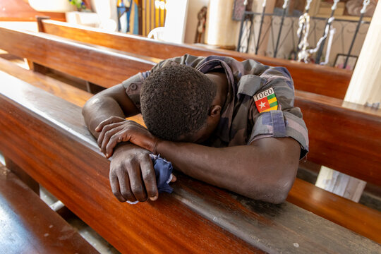 Soldier resting on a church pew, Lome, Togo