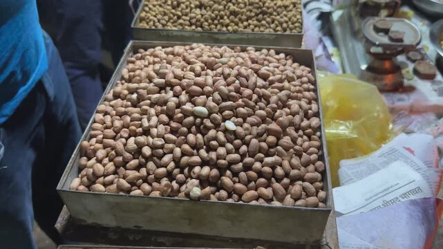 Orbiting view of raw peanut kernels displayed in a metal tray at a local market for commercial sale