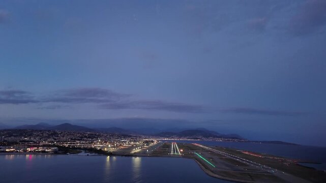 Thrilling cockpit view taken from inside a jet cockpit flying the final approach to the illuminated Nice airport runway o4, with a twilight sky. 4K shot.