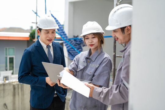 Project manager and engineers review blueprint and laptop during construction inspection, checking specifications, building progress, technical planning, collaboration.