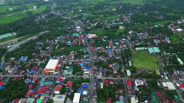 Cinematic aerial view of the commercial center of Goa, Camarines Sur, Philippines, featuring 101 Shopping Center and surrounding businesses along the Governor Jose T. Fuentebella National Highway. Dro