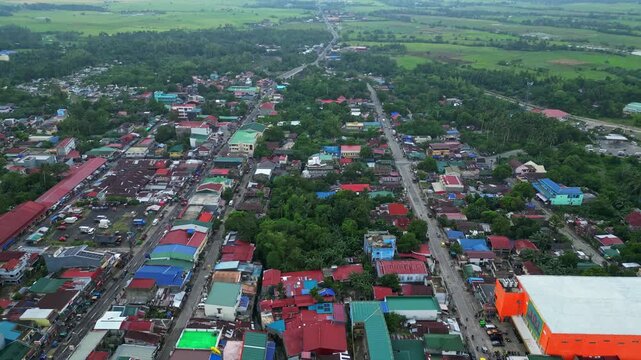 Cinematic aerial view of the commercial center of Goa, Camarines Sur, Philippines, featuring 101 Shopping Center and surrounding businesses along the Governor Jose T. Fuentebella National Highway. Dro