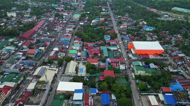 Cinematic aerial view of the commercial center of Goa, Camarines Sur, Philippines, featuring 101 Shopping Center and surrounding businesses along the Governor Jose T. Fuentebella National Highway. Dro
