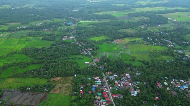 Wide aerial drone view of Goa town in Camarines Sur, Philippines, showing the urban landscape and main transportation corridor along Governor Jose T. Fuentebella National Highway. Footage captures com