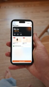 A shopping app shows a Black Friday deal with a running countdown and a discount code. Point of view shot in vertical format with the phone held in the hand. Interface in German.