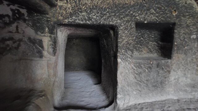 Personal perspective, moving forward into a dark, narrow passage inside an ancient, mysterious house carved right into the rock, revealing the intricate details of its stone walls of Vardzia