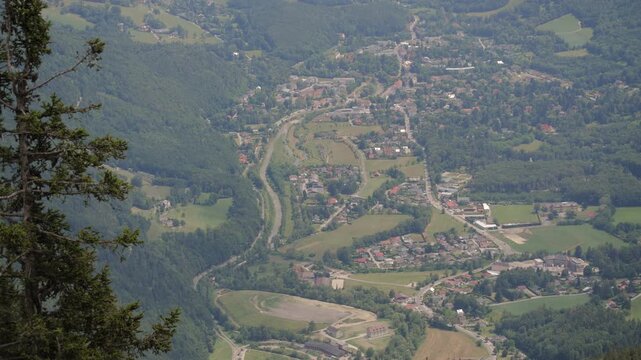 A view shows a mountain valley and a town below with greenery and roads.