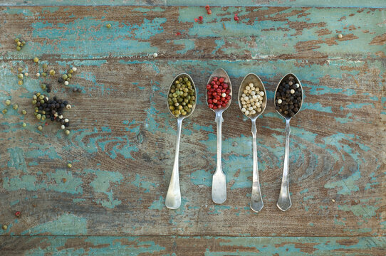 Row of four silver spoons with different sorts of peppercorns