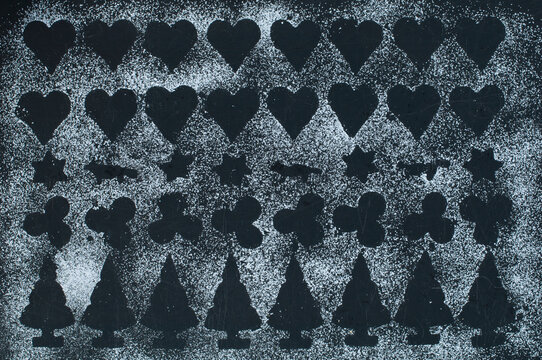 Shapes of Christmas cookies on baking tray, icing sugar