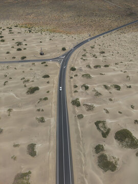 Aerial view of a car driving on a desert road in Famara Dunes