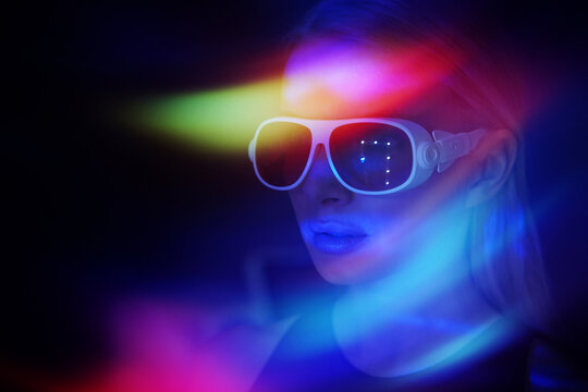 Woman wears VR glasses in neon light exploring the metaverse
