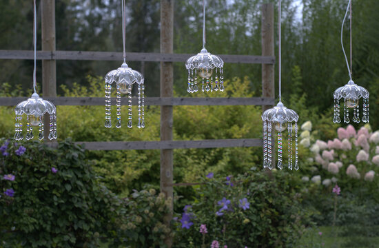 Crystal wind chimes hanging in a garden at dusk. Elegant glass prisms create sparkling reflections and a magical outdoor scene.