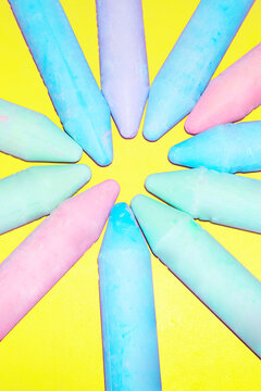 Colorful chalks form a circle on a bright yellow background