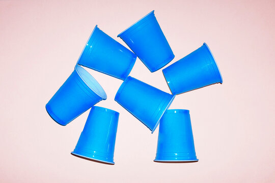 Scattered blue plastic party cups on pink background