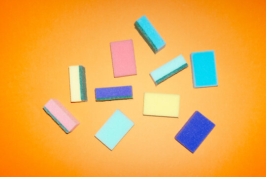 Colorful cleaning sponges scattered on an orange background
