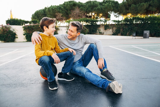 Father embracing son on basketball outdoor court