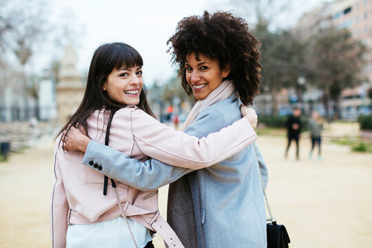 Spain, Barcelona, portrait of two happy women in city park embracing turning round