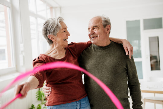 Smiling man and woman enjoy indoor fitness with a hula hoop
