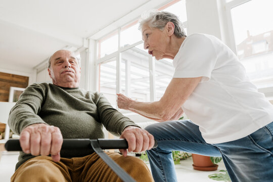 Senior woman cheers on senior man using a rowing machine indoors