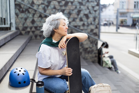 Woman takes a break with her skateboard on city stairs