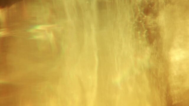 Warm sunlight refracts through a faceted crystal vase, casting flowing golden caustics and abstract glowing patterns in close-up.