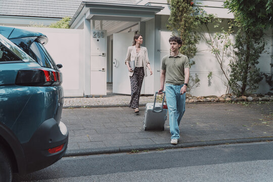 Man and woman leaving home with suitcase for a business trip