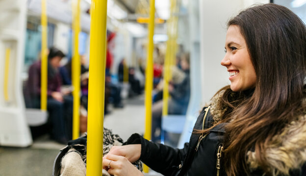 UK, London, happy young woman in an underground train