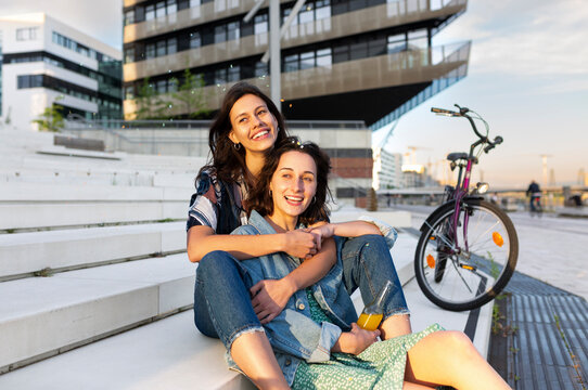 Happy female friends share a warm embrace on urban steps