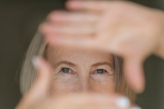 Woman frames her vision with hands in the office