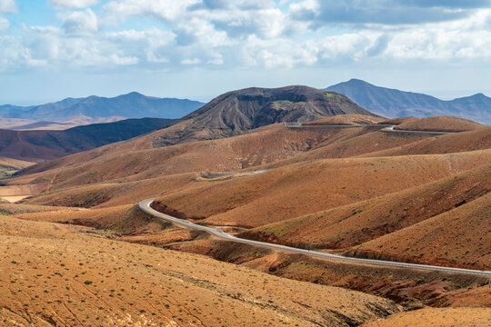 An empty road crosses the dry mountain landscape of Fuerteventura